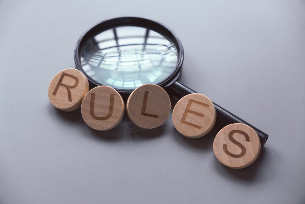 Wooden alphabet of word rules over a magnifying glass.